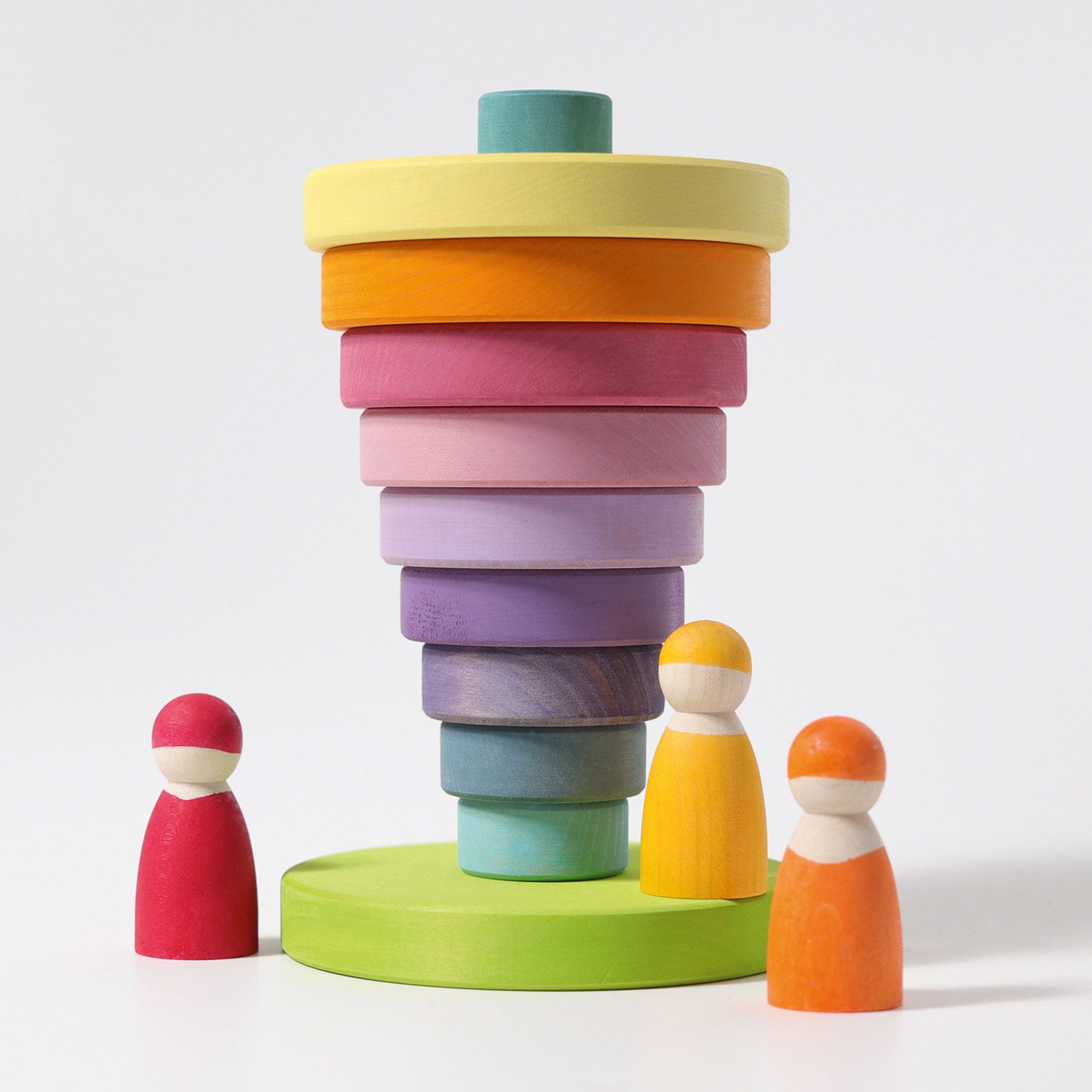 A pastel rainbow coloured conical tower has been arranged upside down.  There are three small wooden people at the base of the tower.