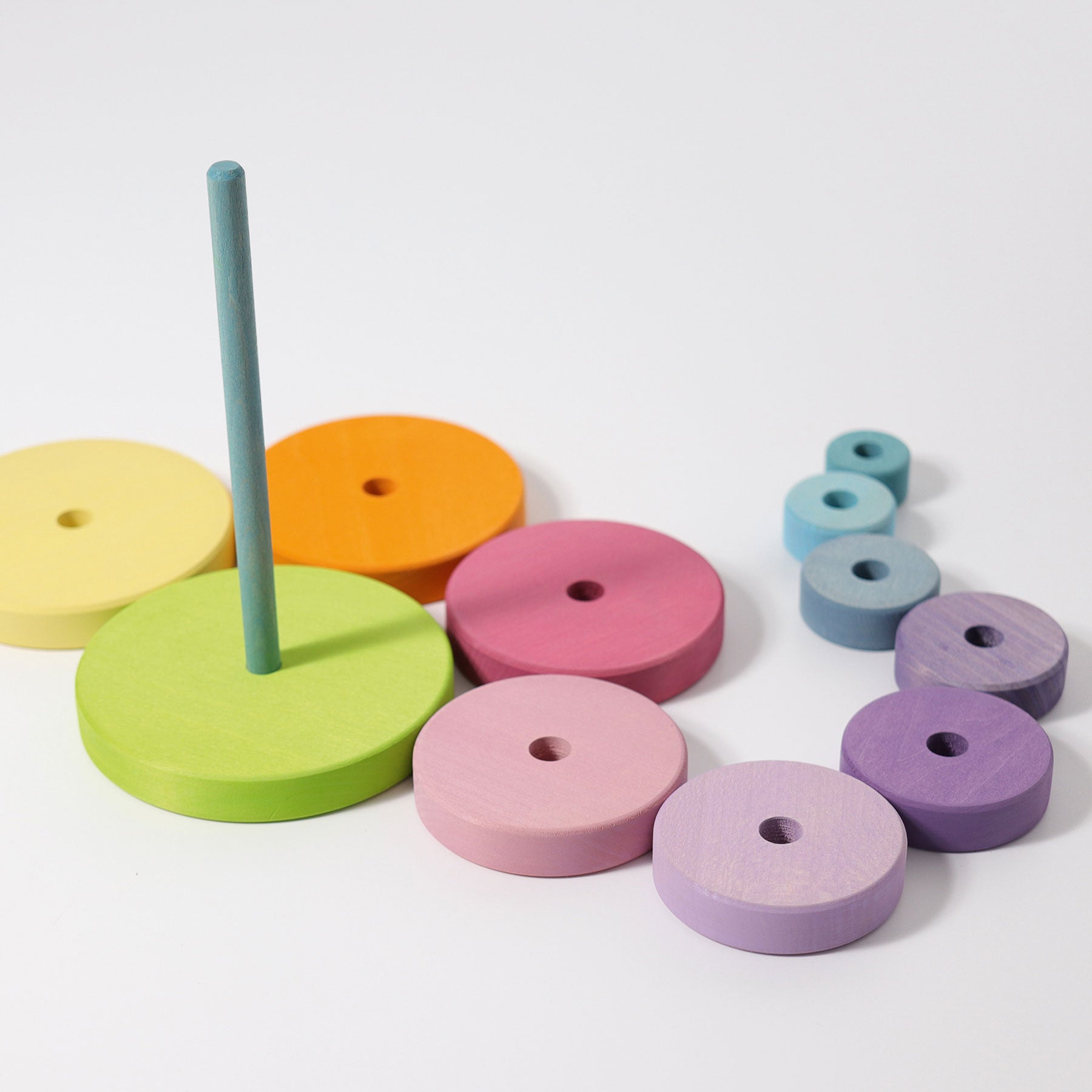 Various pastel coloured wooden circles with holes in the centre lay scattered around one large green disc with long stick protruding from the centre.