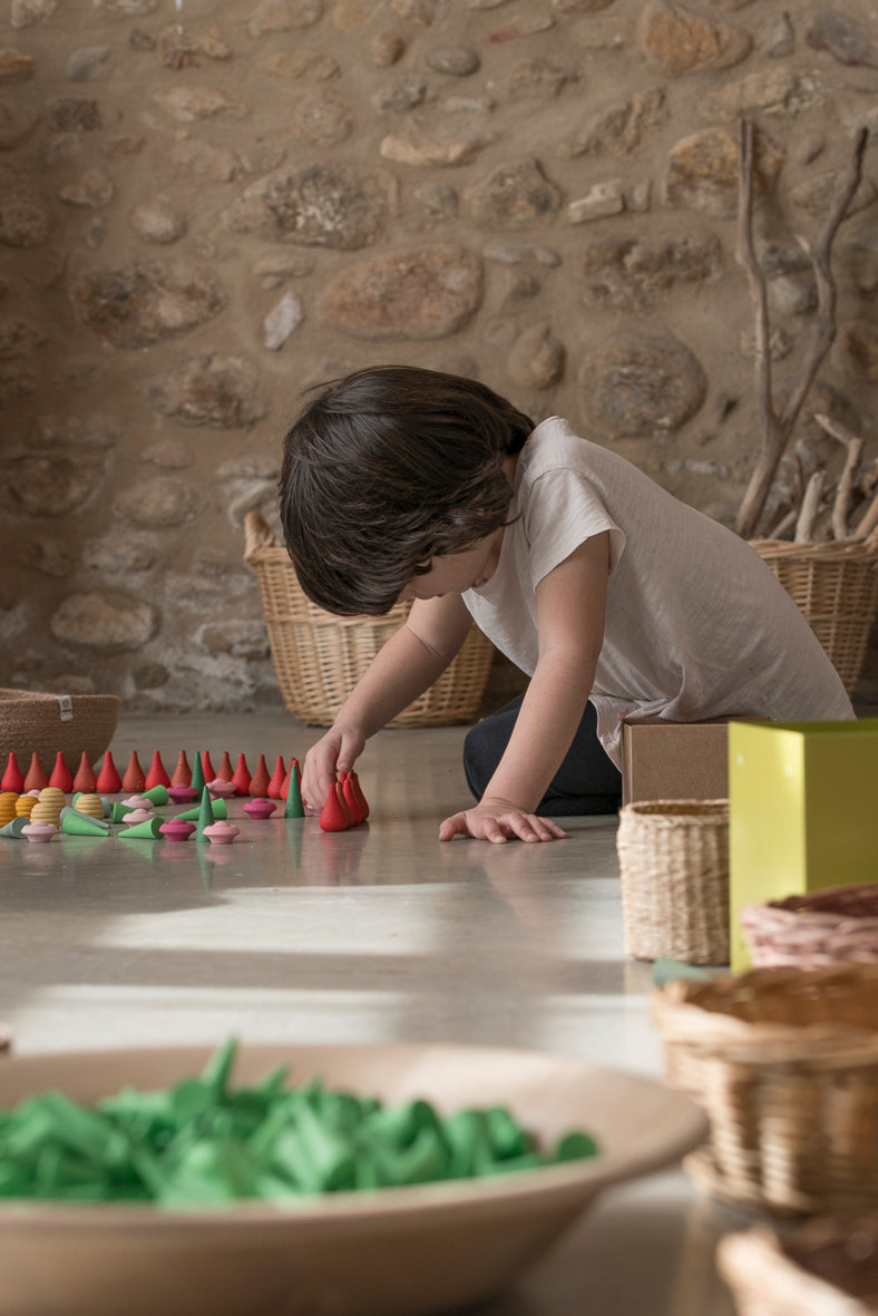 A young child plays with wooden mandala pieces.  They are arranging the wooden pieces into a pattern.